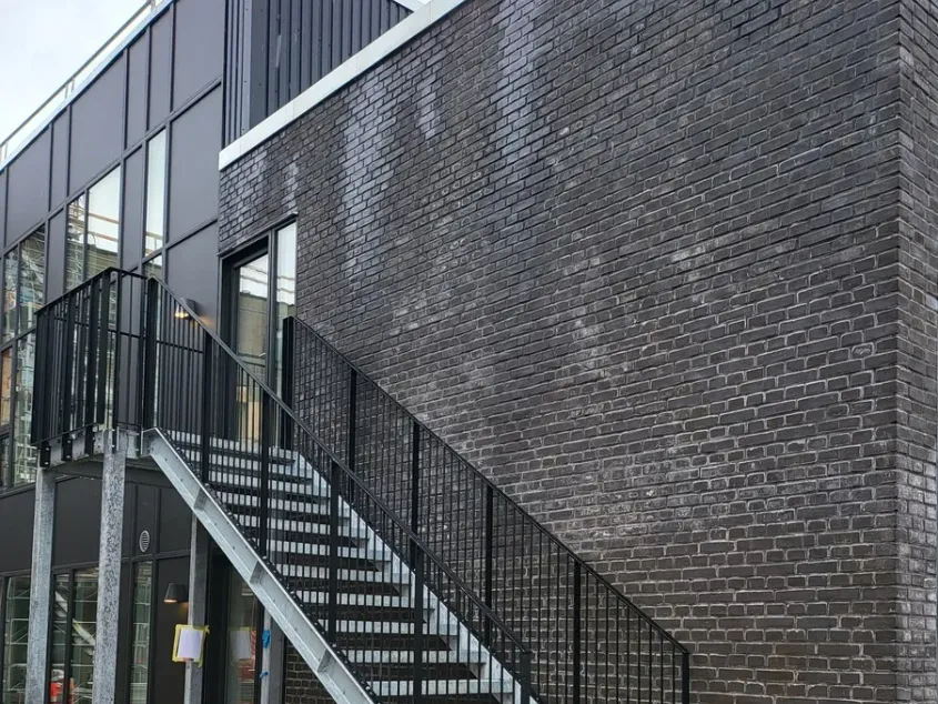 Modern commercial building with a dark brick facade and external staircase